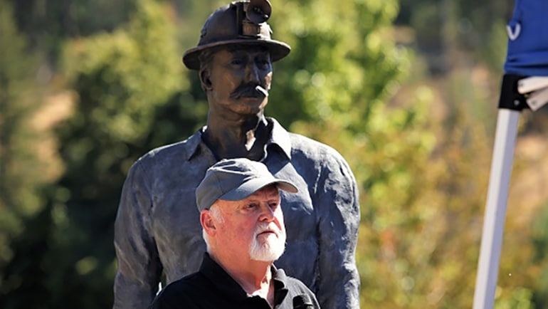 Photo of a man standing in front of the Lucky Friday Miner statue being unveiled